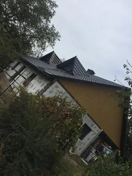 Dom w budowie z dachem krytym dachówką w kolorze grafitowym, widok z dołu