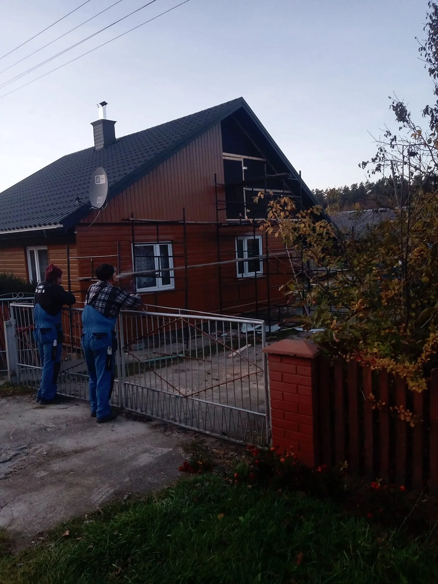 Budynek drewniany w trakcie malowania elewacji, dach kryty dachówką ceramiczną