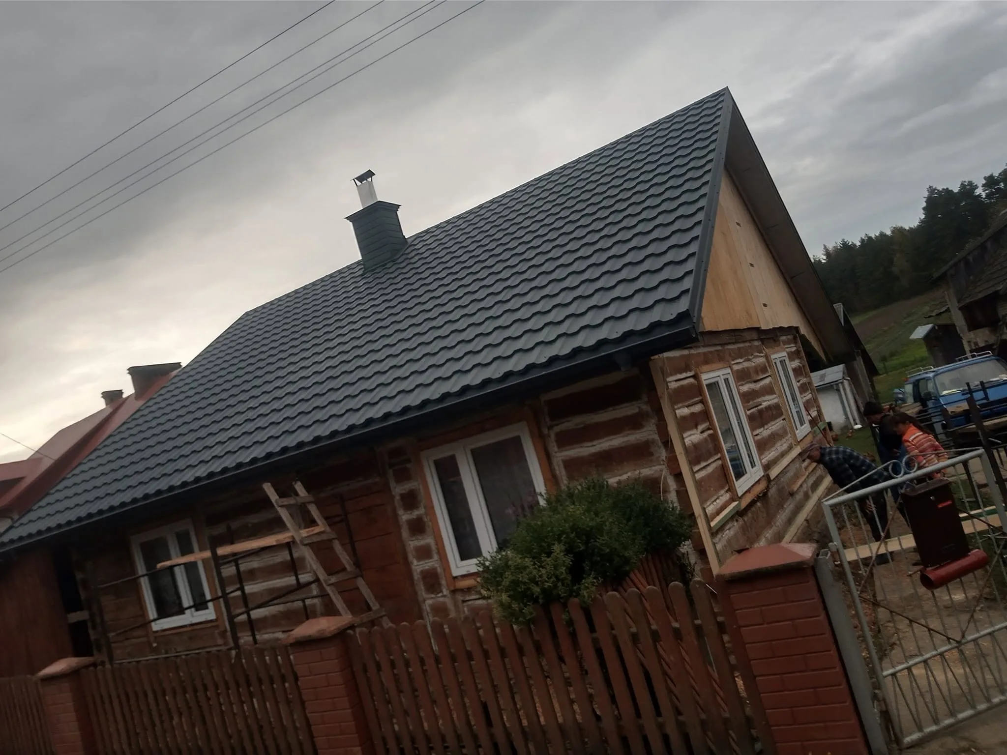 Dom z bali w trakcie remontu elewacji, widoczne rusztowanie